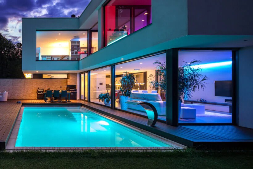 Casa de noche con luces de color y piscina iluminada
